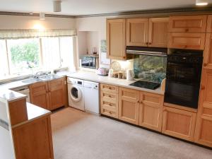 瑟索Keith House的厨房配有木制橱柜、水槽和洗碗机。