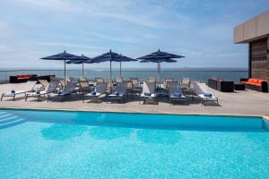 长滩阿乐格利亚酒店的一个带椅子和遮阳伞的游泳池以及大海