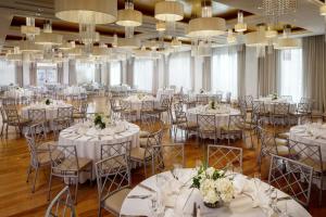 长滩阿乐格利亚酒店的宴会厅配有白色的桌椅和吊灯