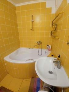 罗夫诺4-км в центрі міста的黄色瓷砖浴室设有浴缸和水槽