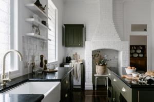 马莱尼墨兰莉小屋酒店的厨房设有水槽和白色砖墙