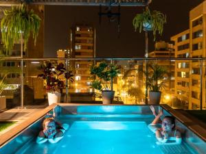 利马Alpes Lima Kennedy Hostel的两人晚上躺在阳台上的游泳池里
