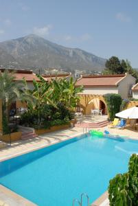 凯里尼亚五指度假简易别墅酒店的一个大蓝色游泳池,背景是一座山