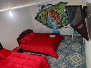 波哥大La Cachaca的一间卧室配有一张红色的床和一幅豹画