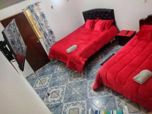 波哥大La Cachaca的一间卧室设有两张带红色床单的床,地面铺有红色
