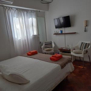 布宜诺斯艾利斯Acogedor apartamento céntrico. Obelisco.的一间卧室配有一张床、两把椅子和电视