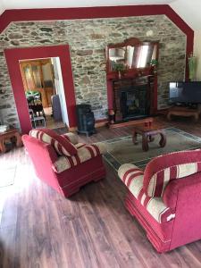 卡斯尔格雷戈里Castlegregory-Seaside 2 Bedroomed Cottage的客厅配有两把椅子和石头壁炉