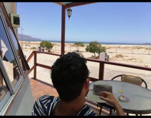 巴伊亚英格莱萨DOMO CAMPING的坐在桌子上,望向海滩的人