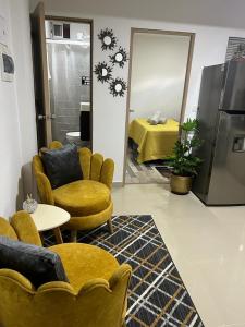 伊塔圭Lindo Apartaestudio cerca al centro的客厅配有黄色椅子、桌子和床