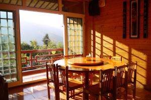 鹿谷乡金台湾山庄的配有大窗户的客房内的一张木桌和椅子
