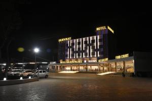 HālolHOTEL GOLDEN PALACE & ROOMS的夜间酒店,停车场内有车辆停放