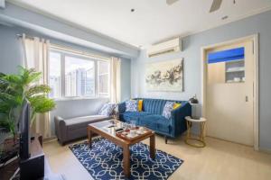 马尼拉BGC Private Apartments的客厅配有蓝色的沙发和桌子