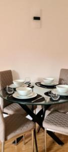 New SouthgateLovely 2 bedroom Flat with Free Parking的一张带盘子和椅子的黑色餐桌