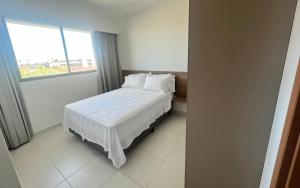 伊波茹卡Mana beach 2 quartos Muro Alto Ipojuca的一间卧室配有一张带白色床单的床和一扇窗户。
