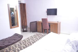 Oba IleAkure Airport Hotel的一间卧室配有一张床、一张书桌和一面镜子