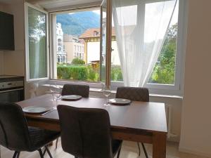 因特拉肯Henry's Apartments Interlaken的餐桌、椅子和大窗户