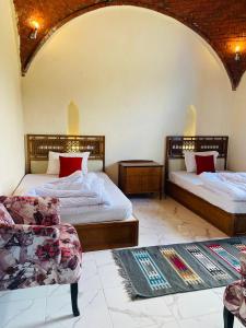 Qaryat at Ta‘mīr as SiyāḩīyahLake House by Tunisia Green Resort的一间卧室配有两张床、一把椅子和一张沙发