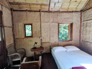 Ban Pang LuangHarvest Moon Valley的一间卧室配有一张床、一张桌子和两个窗户