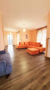 PernikЕлегантен градски апартамент с обширна тераса的客厅铺有木地板,配有橙色沙发。