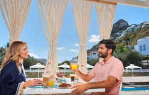 斯基罗斯岛佩里吉利酒店的坐在桌子旁喝橙汁的男人和女人