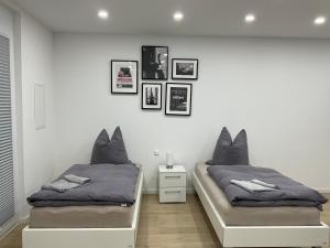 莱因费尔登-埃希特尔丁根Deluxe Apartments Messe Flughafen的一间卧室设有两张单人床,墙上挂有图片