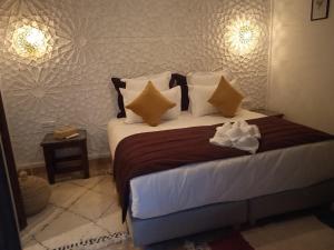 马拉喀什Riad Beni Sidel的一间卧室配有一张大床,提供棕色和白色的枕头