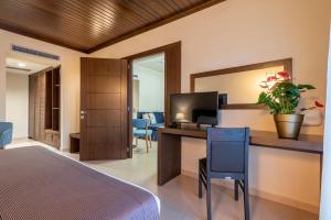 Agios Ioannis Kaspaka港口广场酒店的一间卧室配有一张床和一张书桌及电视