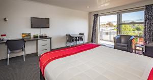 新普利茅斯普基库拉汽车旅馆的配有一张床、一张书桌和一扇窗户的酒店客房