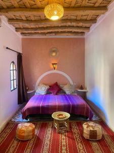 Akhendachou nʼAït Ouffi迪萨蒂尼宾馆的一间卧室配有一张紫色的床和一张桌子