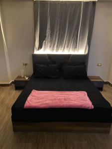 开罗New Cairo lux apt in lux villa basement1的一间卧室配有一张黑色床,上面有粉色毯子