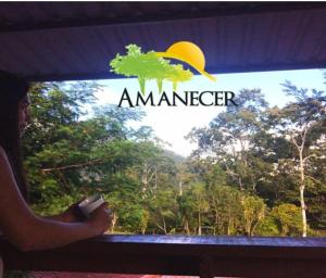 图里亚尔瓦Hospedaje Amanecer的一位女士在亚马逊标志的窗口外望着