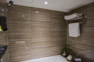 台北柜富旅店 的一间带浴缸和淋浴的浴室,拥有木墙