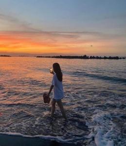 静冈オーシャンビューゲストハウスEat&Stay ROMEY的海滩上水中散步的年轻女孩