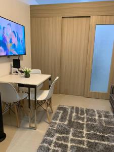 马尼拉Katei elegantly designed 1-bedroom facing amenity的配有桌椅和屏幕的房间