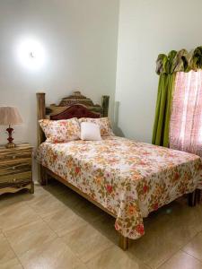曼米湾Cozy Villa的一间卧室配有一张带花卉棉被和桌子的床