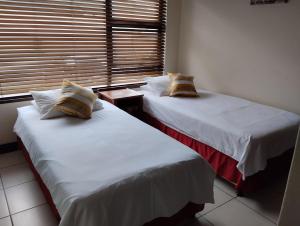 乌旺戈海滩Topanga Holiday Apartment的两张床位于一个房间窗户旁