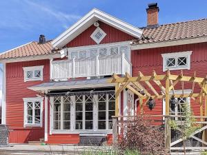 Rindö8 person holiday home in VAXHOLM的红色的房子,设有白色门廊和阳台