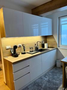 亚霍里纳Pinewood apartment Jahorina的厨房配有白色橱柜和水槽