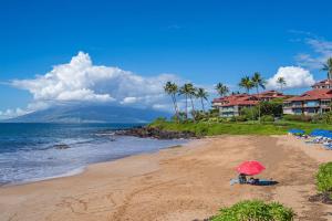 维雷亚Aloha Moon - A Chic and Dreamy Modern Tropical Hideaway!的坐在海滩上的人,戴着红伞