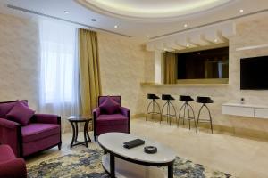 阿可贺巴The Proud Hotel Al Khobar的客厅配有紫色椅子和电视