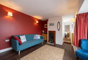 谢林汉姆The Wave - 3 bed beach front home in Sheringham的客厅设有蓝色的沙发和红色的墙壁