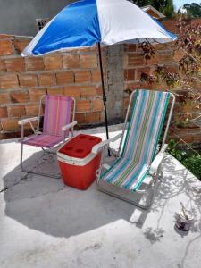 卡马萨里Refúgio sossego (casa de campo)的庭院设有两把草坪椅和一把遮阳伞