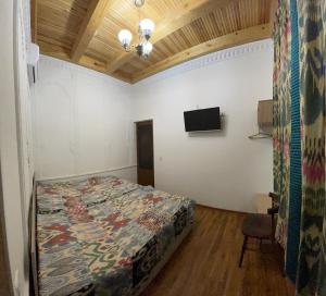 布哈拉Mutara Bukhara的卧室配有一张床,墙上配有电视。