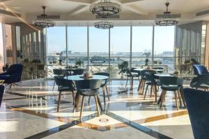 迪拜Miraclz Skyline Tower的用餐室配有桌椅和大窗户