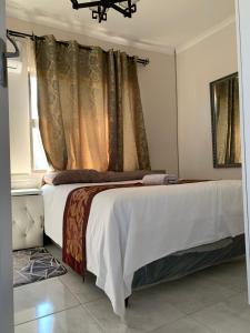 哈博罗内Sekaka Fully Furnished Apartments的一间卧室配有一张带白色床单的床和一扇窗户。