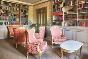 Lurcy-LévisChâteau de Béguin的一个带粉红色椅子、桌子和书架的图书馆