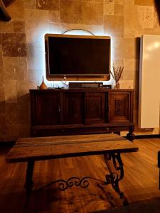 阿特Chez Claude appartement cozy climatisé pour 4 personnes tout confort的坐在木桌边的电视机,配有长凳