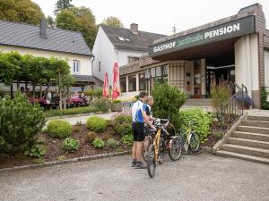 格赖因加斯霍夫足尔特劳伯酒店的两个人站在商店前,骑着自行车