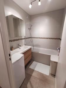 诺瑟尔Appartement Noisiel 77 (proche Disneyland & Paris)的白色的浴室设有浴缸、水槽和镜子