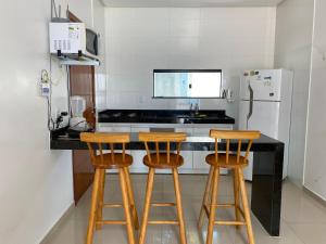 塞古罗港Seu apartamento em Porto的厨房配有2把吧台凳和1台冰箱